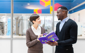 <p>Bioburden in EU GMP Annex 1: Risk Assessment</p>
Employees discussing a book in a lab, with laboratory equipment visible in the background.
