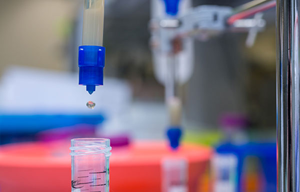 Protein purification 图片捕捉了实验室环境中的一个精确时刻,一支蓝色移液管正在将一个透明液滴注入一个小的透明容器中。