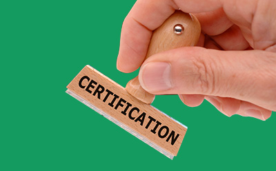 画面描绘了一只手准备盖上标有 "CERTIFICATION"（认证）字样的木质橡皮图章，背景是一片生机勃勃的绿色。