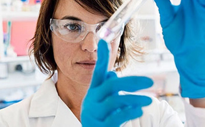 Professional Laboratory Scientist Conducting Experiment 图片显示,一名女性工作人员在实验室里仔细检查装有透明液体的试管。