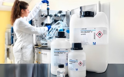 Affinity chromatography with Eshmuno® resins 4 different sizes of Affinity chromatography with Eshmuno® resin bottles sit on a black counter with a scientist working on a piece of machinery in the background