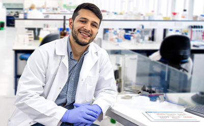 <p>Transforming Pharma Operations with Generative AI: From Data Silos to Intelligent Insights</p>
Scientist in a lab environment wearing a lab coat and protective gloves sitting at desk