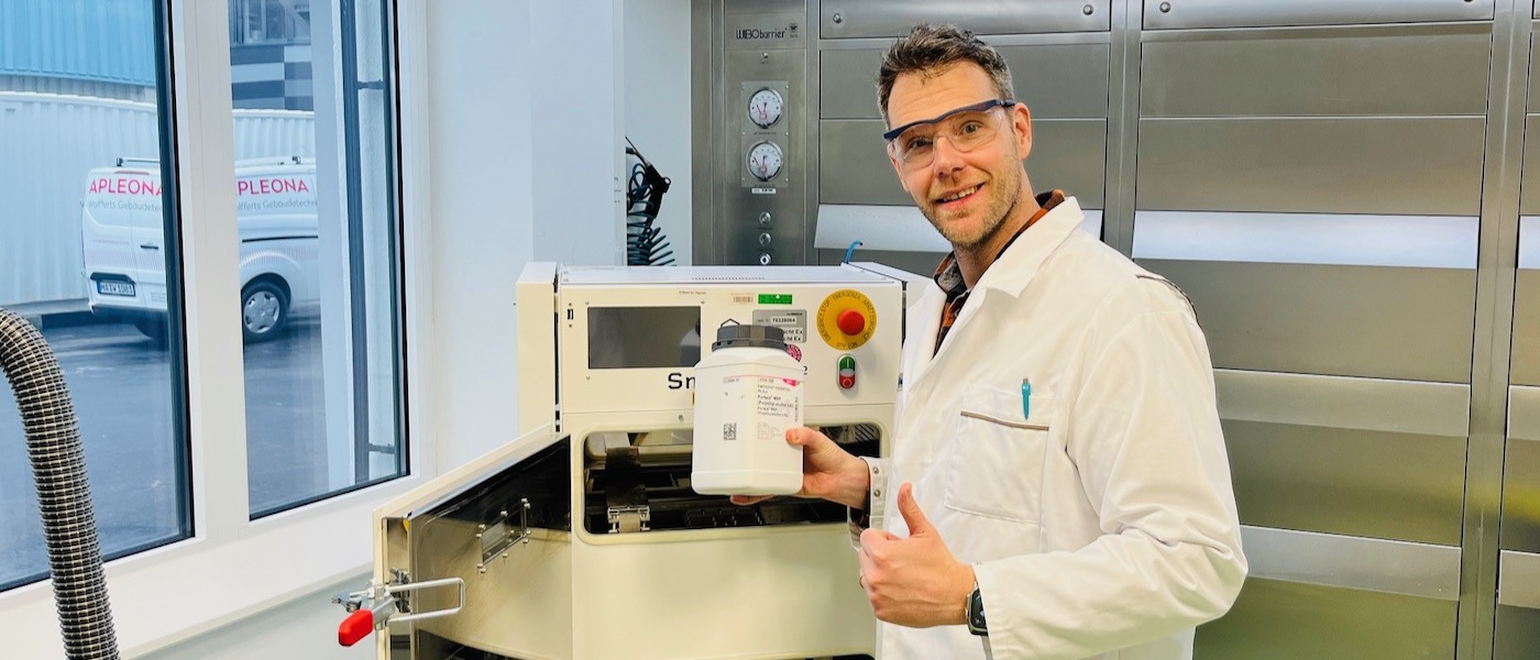 Thomas Kipping in lab Thomas Kipping wears safety glasses and a lab coat standing next to a laser 3D printer.