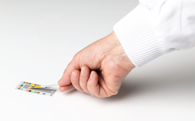 A user properly placing a dipped MQuant® Test Strip on the color reference card prior to reading by the MQuant® StripScan App on a device A user properly placing a dipped MQuant® Test Strip on the color reference card prior to reading by the MQuant® StripScan App on a device