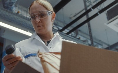 Packaging Improvements Supplier Toolkit Person in a lab coat examining bottle and packaging materials