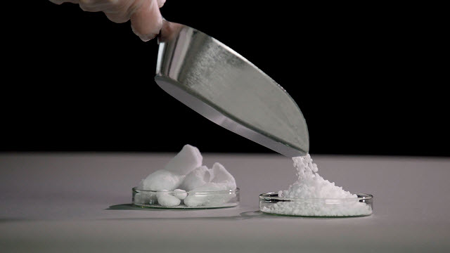 <p>Granulated Raw Materials for Pharmaceutical Processes</p>
White granulated material is being poured into a petri dish on a gray counter.