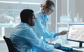 Two lab workers looking at a computer screen.