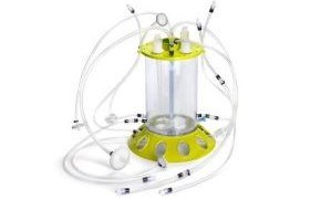 Mobius 3L Bioreactor Mobius® iFlex Bioreactor 200 L in perfusion mode. A clear cylinder with a yellow base and top, with clear tubes coming out all around.