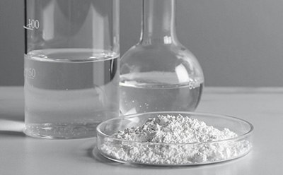 Two beakers with liquid in them and a petri dish with powder in it.