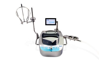 A Sterility Testing Peristaltic Pump. It has a modern design with a digital display screen on the top. The main body of the pump is silver and black with blue accents around the control panel. Attached to the pump are two transparent tubes leading to a metal probe and a plastic component. The background is white.