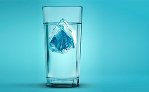 The image depicts a tall, clear glass filled with water, featuring a large, blue-tinted ice cube floating in the center against a turquoise background, exuding a cool and refreshing vibe.