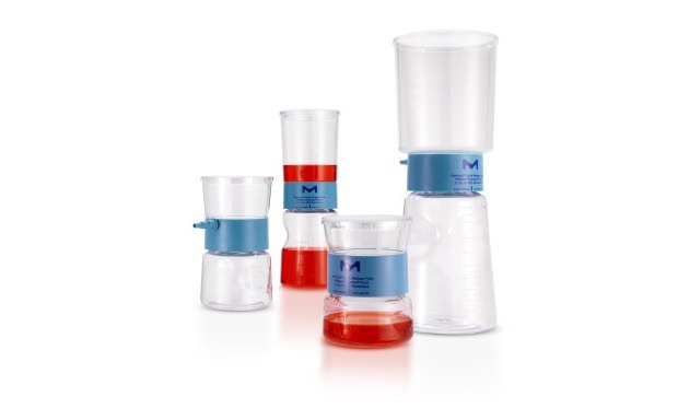 A collection of five laboratory volumetric tools with varying amounts of liquid. From left to right, there is a small beaker with red liquid reaching the measurement line, a graduated cylinder half-filled with red liquid, another graduated cylinder with a smaller amount of liquid at the bottom, an empty volumetric flask on top of an upside-down beaker, and finally, a large beaker half-filled with clear liquid. The tools are marked with measurement lines and are placed against a white background.