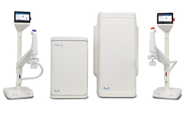 Two medical devices on stands with screens, one red and one blue, alongside a compact white unit and a larger white box. All devices feature the M logo.