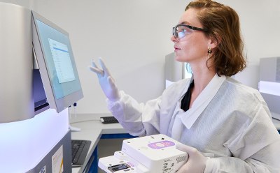 Female lab technician with lab protection cloth working on a computer.