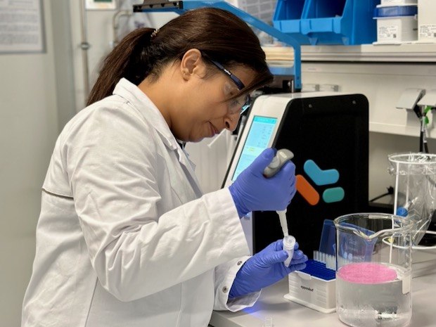 Mehta lab Aditi wears PPE and uses a pipette to extract a solution in the lab.