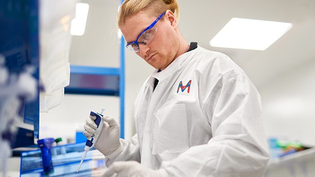 Male lab technician with blond hair in lab protection clothes is working on an experiment.