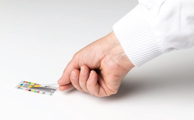 A user properly placing a dipped MQuant® Test Strip on the color reference card prior to reading by the MQuant® StripScan App on a device A user properly placing a dipped MQuant® Test Strip on the color reference card prior to reading by the MQuant® StripScan App on a device