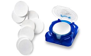 Pile of Millipore filter membranes with stack of filters in plastic container.