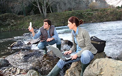 Two scientists testing the water at a river. Two scientists testing the water at a river.
